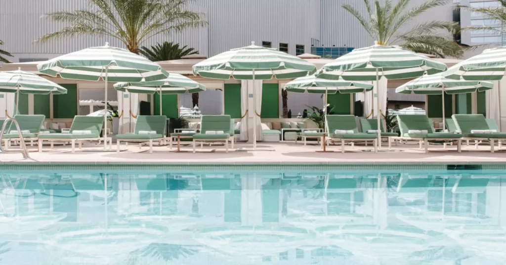Green-and-white striped umbrellas, lounge chairs, and private cabanas at Park MGM Pool Las Vegas